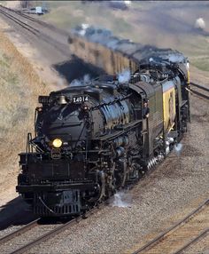 a black train traveling down tracks next to a field