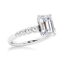 an emerald cut diamond ring with diamonds on the band