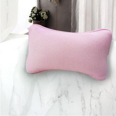 a pink pillow sitting on top of a white counter next to a window and potted plant