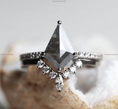 a diamond ring sitting on top of a piece of white sand next to a rock