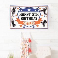 a happy birthday banner hanging on the wall above a white chair and potted plant