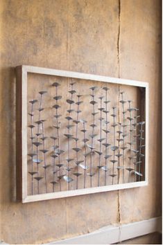 a metal art piece hanging on the wall next to a window in a room with stucco walls