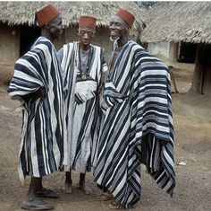 three african men standing next to each other in front of thatched roof huts with grass roofs