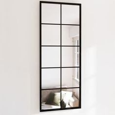 a mirror that is on the wall in front of a couch and window sill