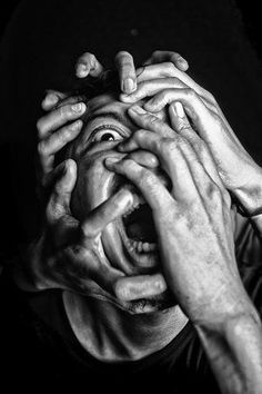 several hands covering the face of a man