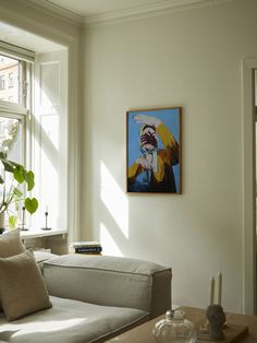 a living room filled with furniture and a painting hanging on the wall next to a window