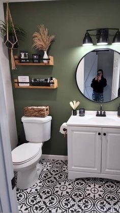 a person taking a photo in the mirror of a bathroom with black and white floor tiles