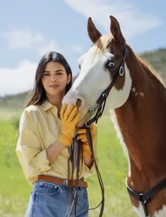 a woman standing next to a brown and white horse