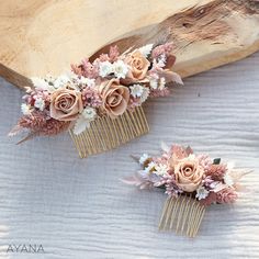 two hair combs with flowers on them sitting next to a piece of driftwood