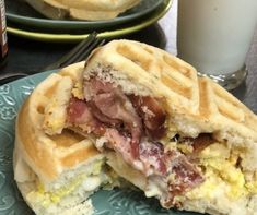 a waffle sandwich cut in half on a blue plate with a glass of milk