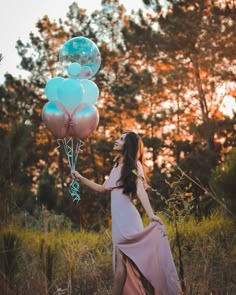 a woman in a pink dress holding some balloons