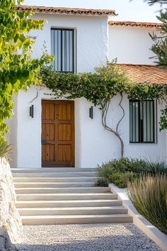 a white house with steps leading up to the front door and trees in front of it