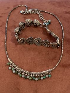 "This is an authentic Brighton necklace and bracelet. They are not technically a pair but the do go nicely together. The necklace is silver with bluish beads hanging of a silver filigreed bar. It has the heart clasp and a heart dangling charm. It measures 15.5\" long not including the extension piece. The bracelet in silver linked hearts. Every other heart has black rhinestones imbedded in the face of the heart. It measures 7\" long not including the clasp... 8.5 including the open clasp." Bracelet In Silver, Woodland Hills, Costume Jewelry Necklaces, Premier Designs, Necklace And Bracelet, Black Rhinestone, Silver Filigree, Heart Bracelet, Charm Bracelets