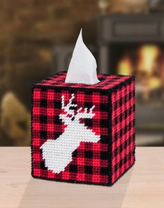 a red and black plaid tissue box with a white deer design on it's side