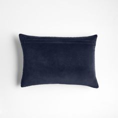 a dark blue velvet pillow on a white wall