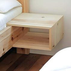 a bed with a white comforter on top of it next to a wooden nightstand