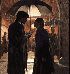 two people standing under an umbrella in the rain