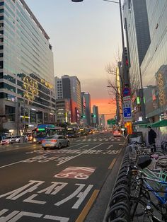 a city street filled with lots of traffic and tall buildings at sunset or sunrise time