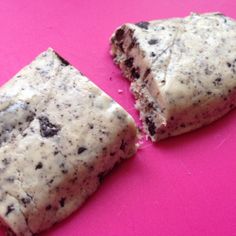 two pieces of chocolate chip cookie on a pink surface