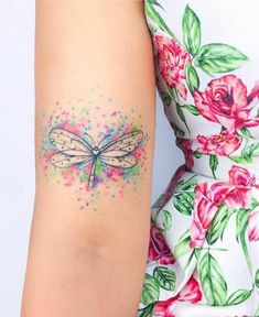 a woman's arm with a dragonfly tattoo on the left side of her arm