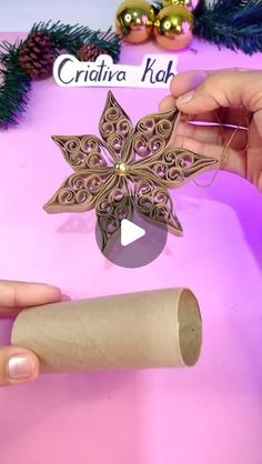 someone is making a paper snowflake ornament on a pink table with christmas decorations