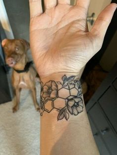 a person's hand with a tattoo on it and a dog in the background