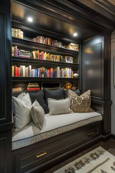 a room with bookshelves filled with lots of books and pillows on top of it