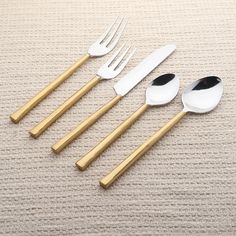 five gold and white utensils are lined up in a row on the floor