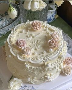 a wedding cake with white frosting and pink roses