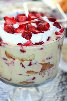 three small desserts with strawberries and cream in them on a white tablecloth