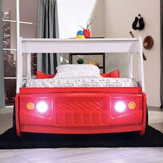 a bed with red pillows and white headboard is in the middle of a room