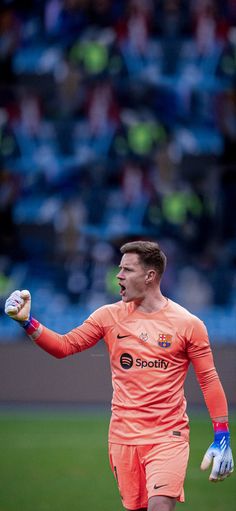 a soccer player in an orange uniform holding his hands out