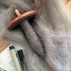 a close up of a wool and wooden object on a table next to some pens