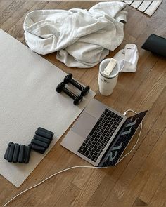 an open laptop computer sitting on top of a wooden floor next to yoga mats and dumbbells