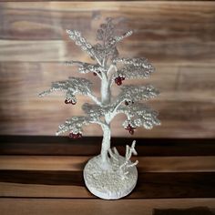 a small white tree with red berries on it