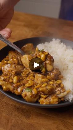 a person is spooning some food out of a bowl with rice on the side