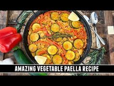 a large pan filled with vegetables on top of a wooden table next to utensils