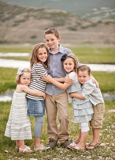 a group of young children standing next to each other on top of a grass covered field