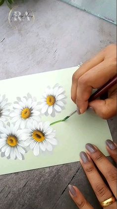 someone is painting daisies on a piece of paper