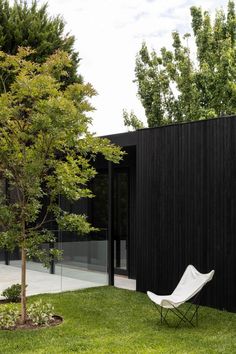 a white chair sitting on top of a lush green field next to a black building