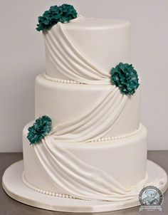 a three tiered white wedding cake with green flowers