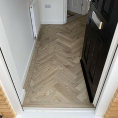 the door is open to reveal an empty room with wood flooring and white walls