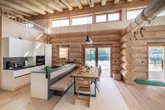 a kitchen and dining area in a log cabin with wood flooring, white walls and ceiling