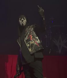 a man in a black hoodie is standing on stage with his hands up to the side