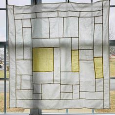 a white and yellow quilt hanging in front of a window