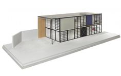 an architectural model of a house on top of a white platform with wood and glass panels