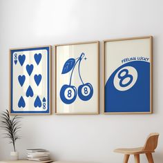 three blue and white posters hanging on the wall above a wooden table with a potted plant