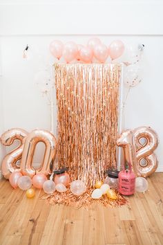 balloons and streamers in the shape of numbers are arranged on a wooden floor next to a balloon column