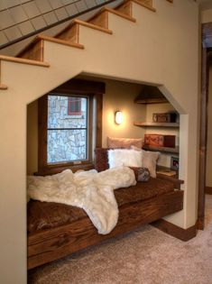 a bed sitting under a window next to a stair case in a room with carpet on the floor