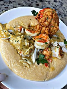 a white plate topped with shrimp and grits